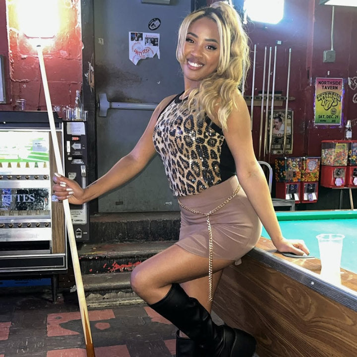 Side view of the Sidonie Chapelain leopard print sequin halter tank top styled with a mini skirt and knee high boots